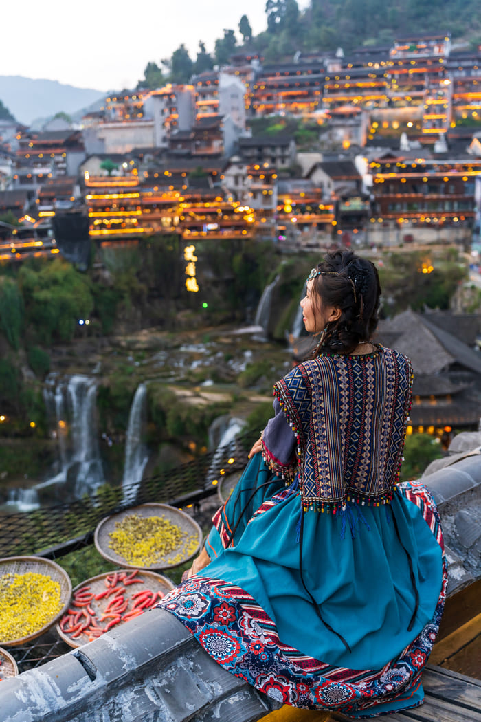 Mujer usando vestimenta típica china, observa paisaje de la ciudad de lijiang